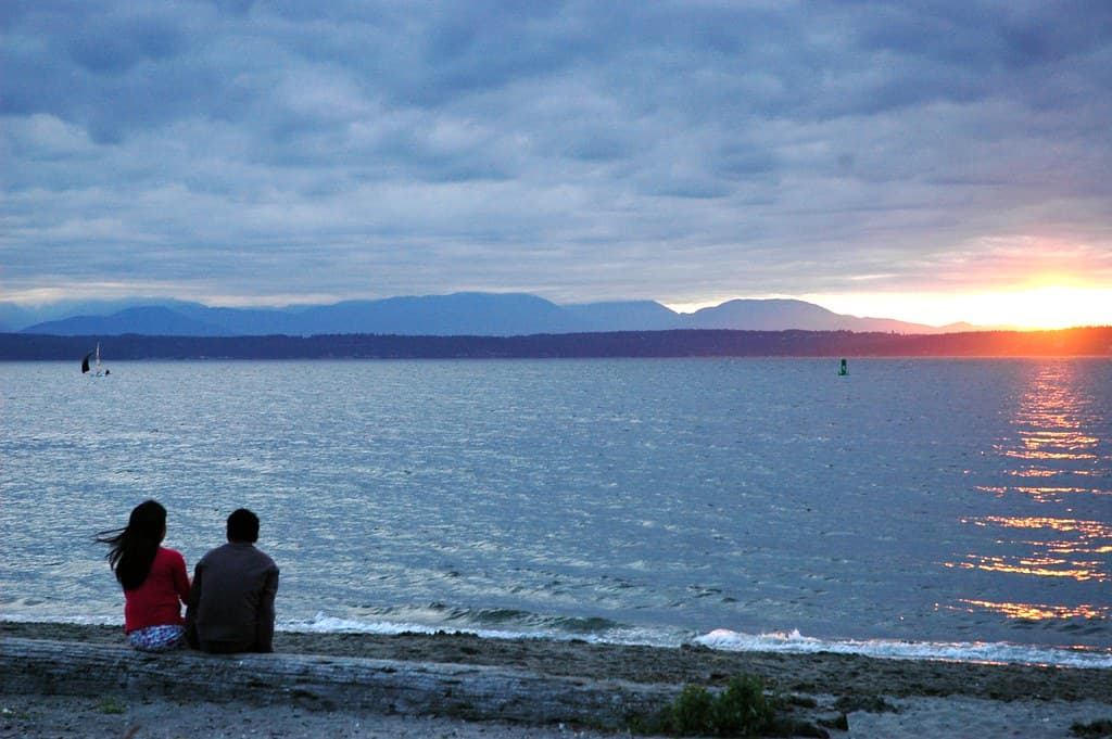 A couple enjoying sunset at Golden Gardens beach, warm night, cool blue light, gloomy weather and rain being appreciated! Seattle, Washington, USA