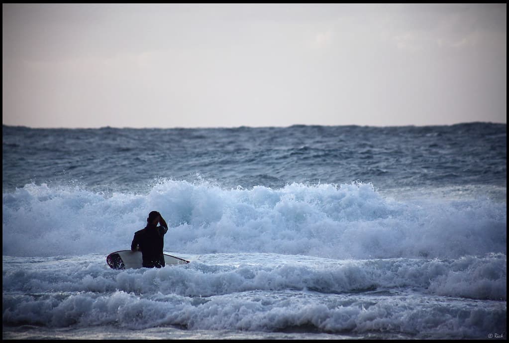 Surfer facing big waves at the "Banzai Pipeline"
