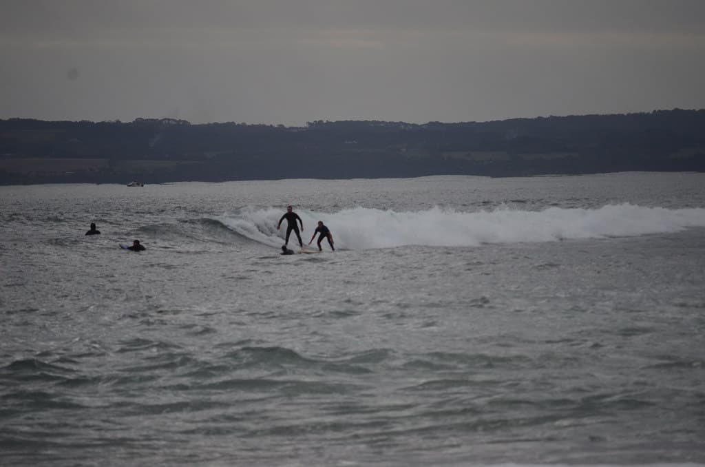 Surfers riding a wave at Flynn's Beach
