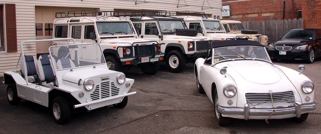 Old cars at Copley Motorcars, Needham MA: 1967 Austin Mini Moke, unidentified (yet) MG roadster, and a row of Land Rover Defenders