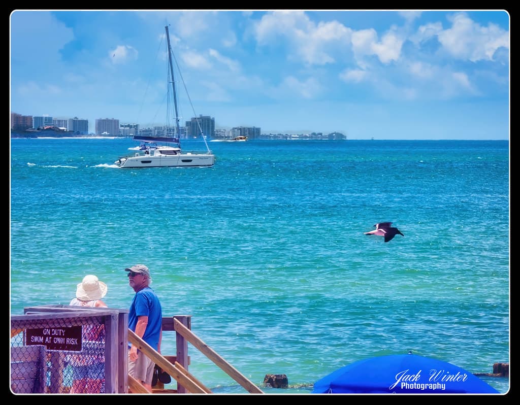 Tourists watch a sailboat transit Hurricane Pass.
