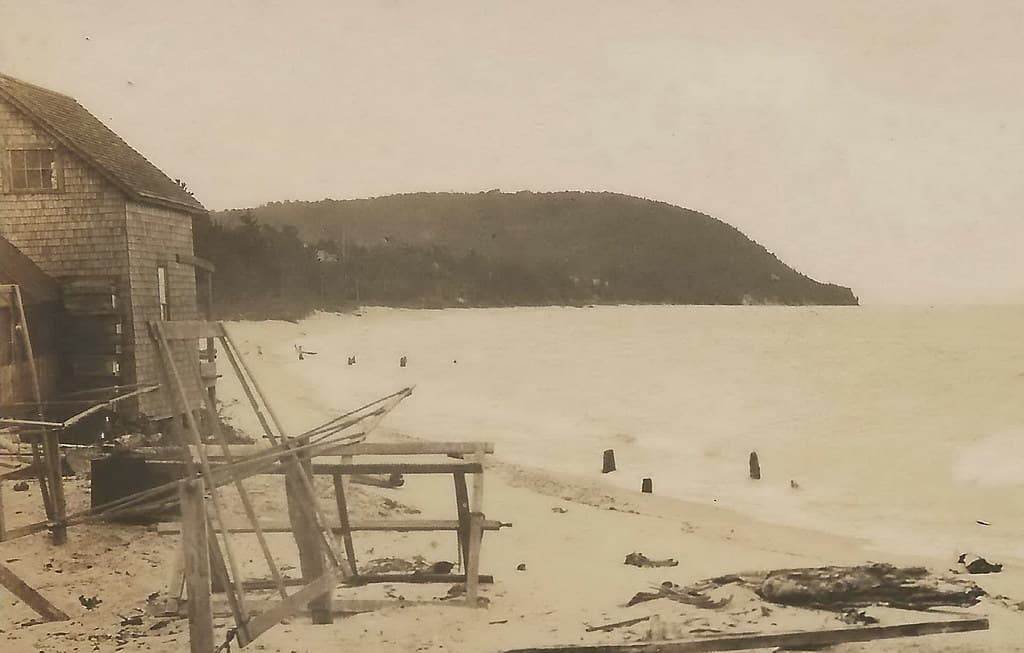 NW Leelanau Leland MI RPPC c.1910 BEFORE HARBOR Carp River Outlet & Old Commercial Fishing Shanty on Beach looking South to Pyramid Point from the Town Beach looking Southwest PHOTOGRAPHER UNK3