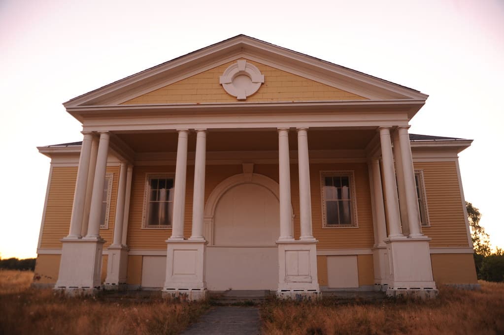 Abandoned yellow & white military Fort Lawton gymnasium, sets of pillars, grasslands, twilight, holy land, Discovery Park, Magnolia Bluff overlooking Puget Sound, Seattle, Washington, USA