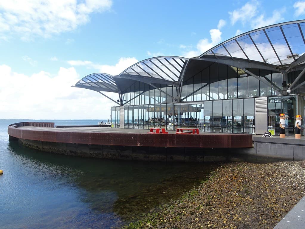 Geelong. Cafe on the pier on Corio Bay. Note the Geelong Baths Swimming Club painted bollards on the edge of the esplanade.