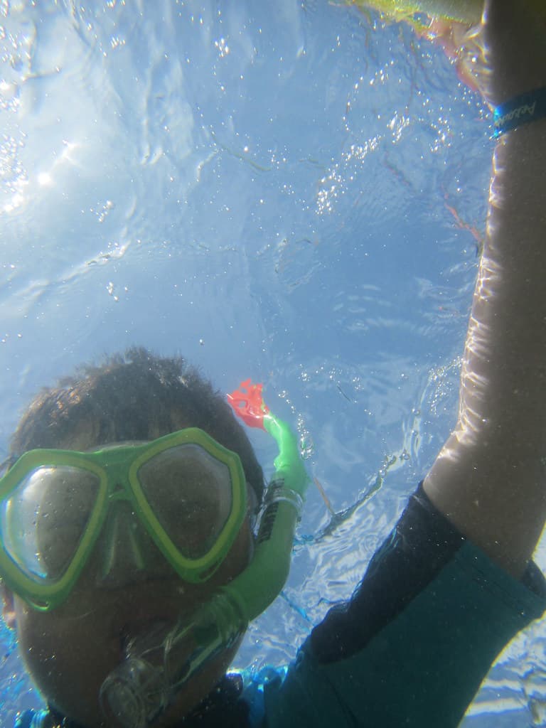 Isaac snorkelling underwater with pool noodle