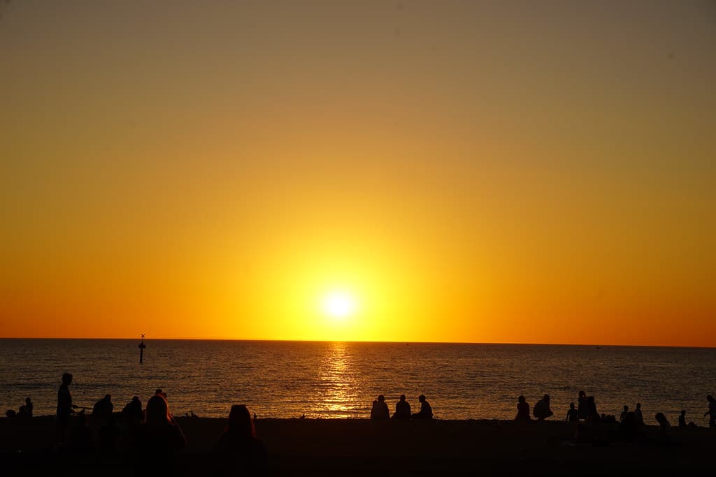 Beachgoers watching the sunset at Mordialloc Beach
