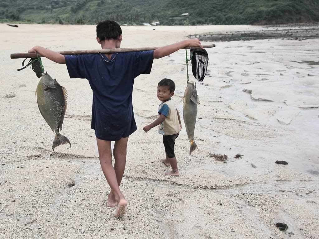 A boy carrying fish in Mawun beach Lombok