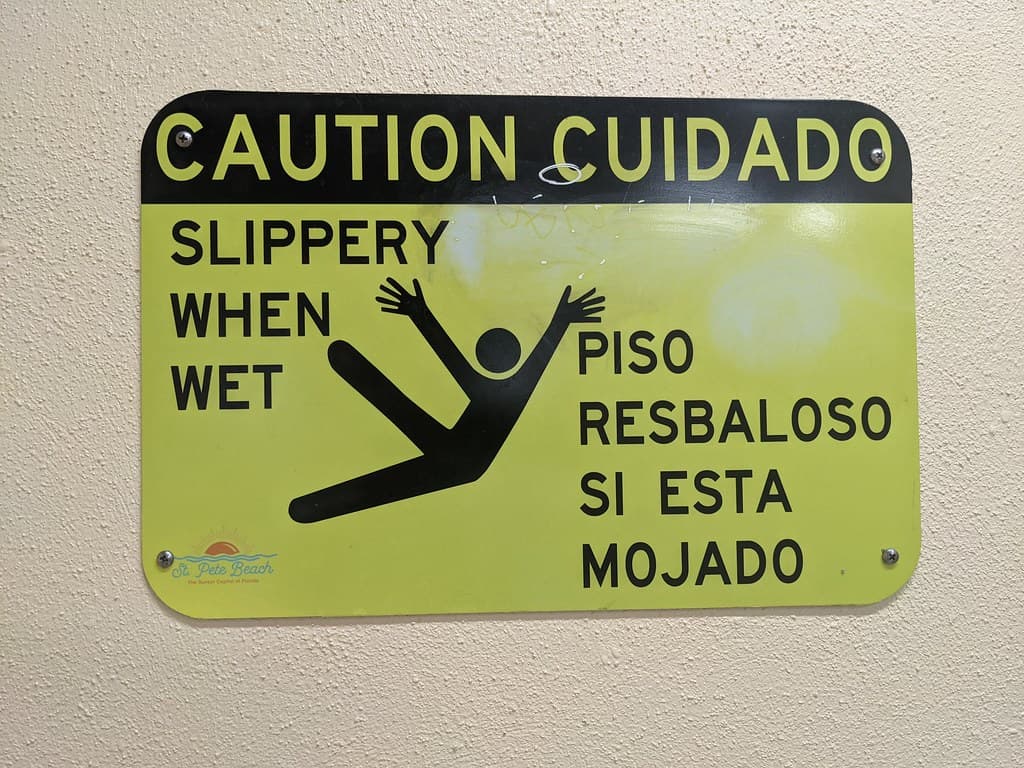 "Caution: Slippery when wet" sign with weirdly detailed hands