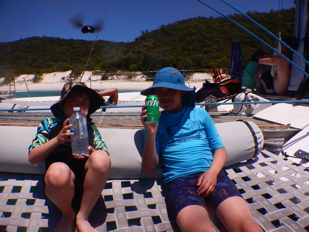 Liam and Isaac enjoying cold drinks after snorkelling at Chalkies Beach