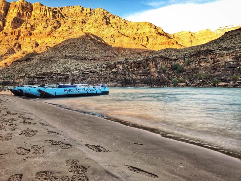 Arizona River Runners S-rig raft and footprints in the sand beach of the Colorado River in Grand Canyon National Park, Arizona